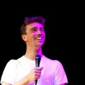 Sam Davis on stage, laughing, mic in hand