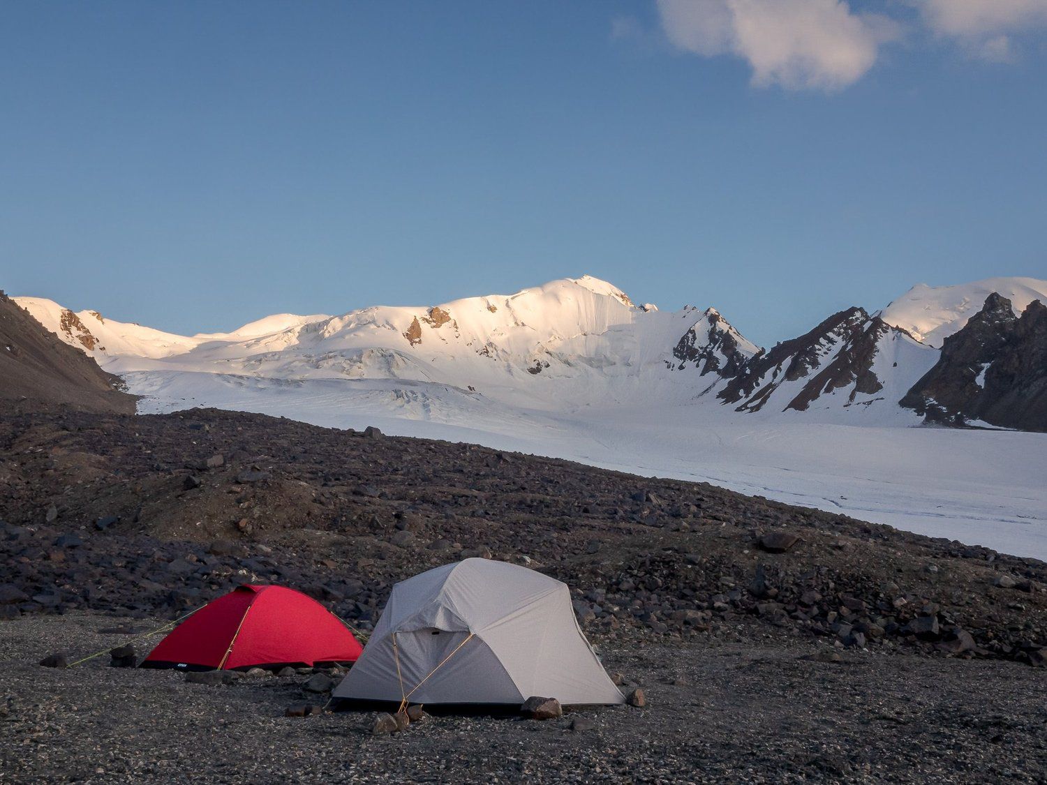 Two tents on moraine looking out over glaciers and peaks at sunset