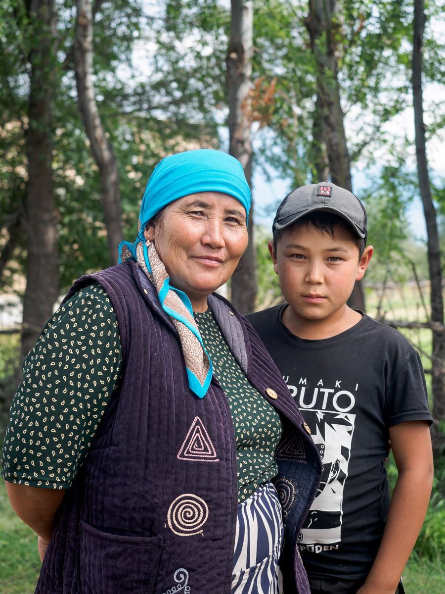 A Kyrgyz mother in a headscarf and her teenage son standing together